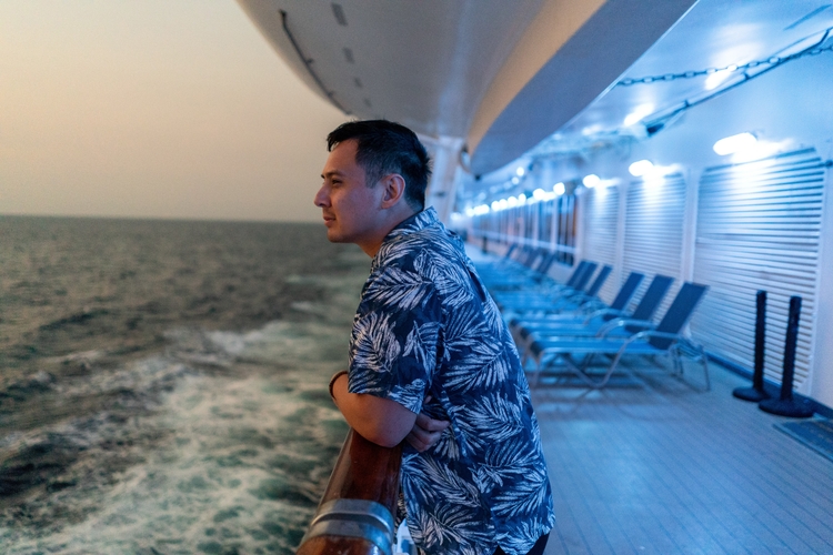 man on cruise ship at night by ocean